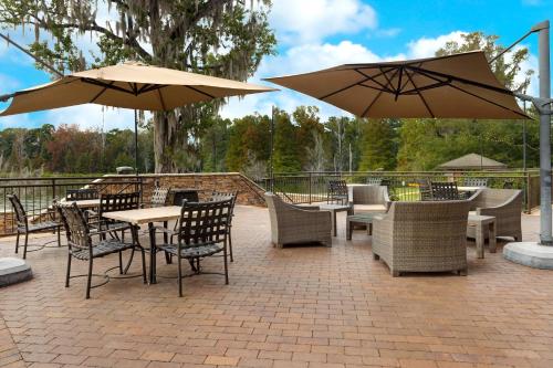 patio ze stołami, krzesłami i parasolami w obiekcie Staybridge Suites Tallahassee I-10 East, an IHG Hotel w mieście Tallahassee