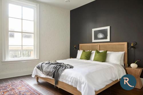 um quarto com uma grande cama branca com almofadas verdes em Roami at St. Charles em Nova Orleães