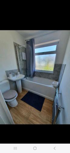a bathroom with a toilet and a sink and a window at Lovely 3 bedroom house free parking in Luton