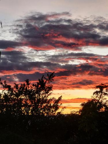a sunset with clouds and trees in the foreground at Quinta Paolita in Tumbabiro