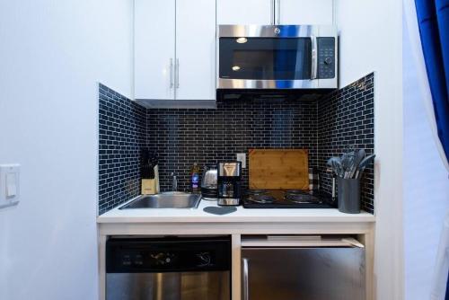 een keuken met een wastafel en een magnetron bij 69-4B Modern Lower East Side 1BR PRIME LOCATION in New York