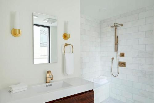 a white bathroom with a sink and a shower at Roami at St. Charles in New Orleans