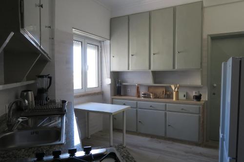 a kitchen with white cabinets and a table in it at Alvalade SkyView CoLiving in Lisbon