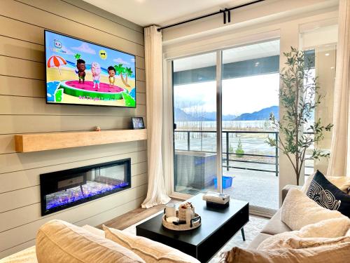 a living room with a tv and a couch and a table at Dreamy Panoramic Lakeview 1 Bedroom plus Den in Harrison Hot Springs
