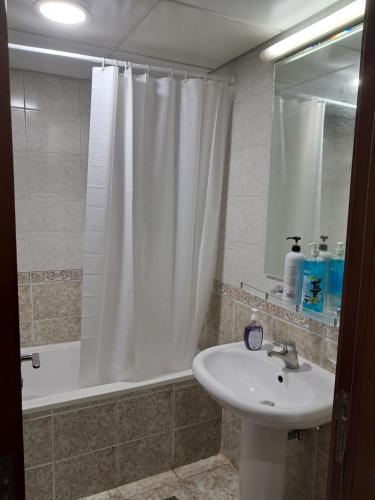 baño con lavabo y cortina de ducha en Top House Hostel en Abu Dabi