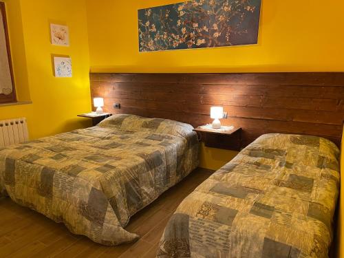 2 camas en una habitación de hotel con paredes amarillas en A casa di Bice, en Case Nuove