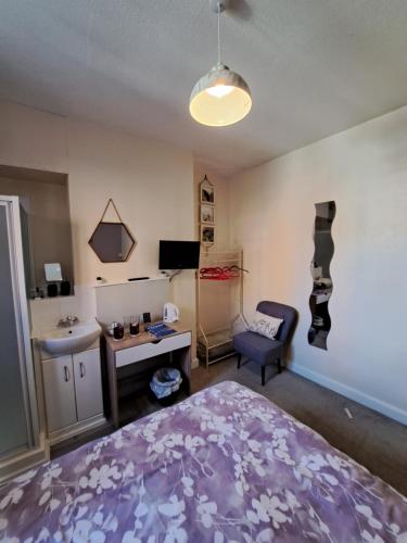 a bedroom with a bed and a desk and a chair at Lyndale Guest House in Weymouth