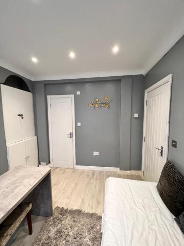 a bedroom with gray walls and a bed and a table at ID’s place in Abbey Wood