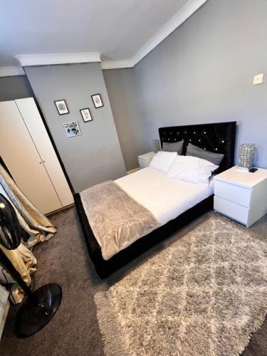 a bedroom with a large bed with a black headboard at ID’s place in Abbey Wood