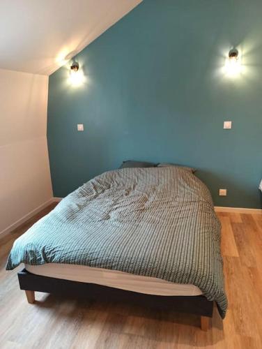a bed in a bedroom with a blue wall at Le Perchoir in Saint-Jans-Cappel