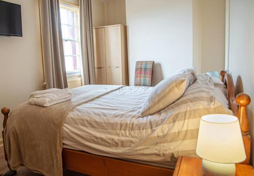 1 cama en un dormitorio con lámpara y mesa en The Plough Inn, en Snaith