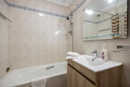 uma casa de banho com um lavatório e uma banheira em Apartamento Meia Praia em Lagos