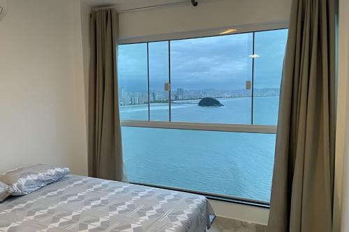 - une chambre avec une grande fenêtre donnant sur l'eau dans l'établissement Apartamento Paraíso da Ilha Porchat ! *Novíssimo!*, à São Vicente