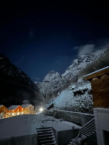 una montaña cubierta de nieve por la noche con las luces encendidas en 4 Stinët, en Valbonë