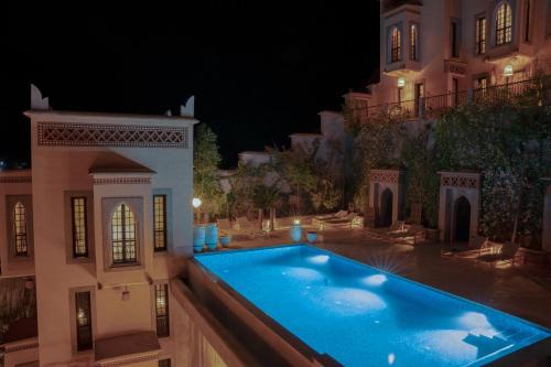 Tamellalt的住宿－Eden Boutique Hotel，夜间在房子前面的游泳池