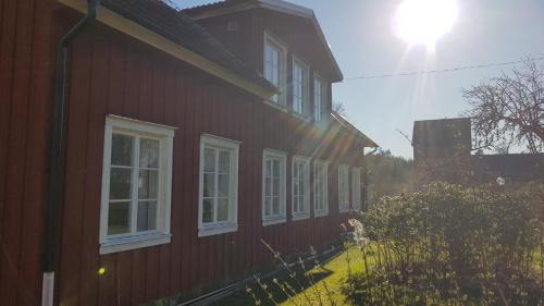 una casa roja con ventanas blancas en el lateral. en Sörgårdens gästlägenhet 1-4 personer, en Köping