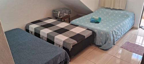 a room with two twin beds and a chair at kitnet em São João Del Rei, a 11km de Tiradentes MG in São João del Rei