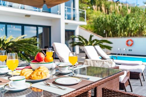 a table with food and glasses of orange juice at Villa Alex,pool and ocean view in Calheta