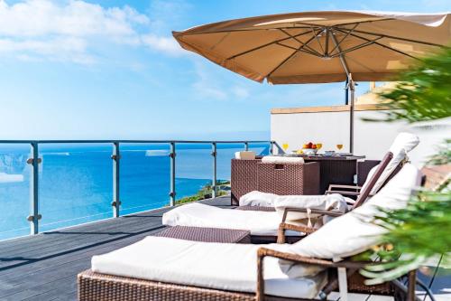 a deck with chairs and an umbrella and the ocean at Villa Alex,pool and ocean view in Calheta