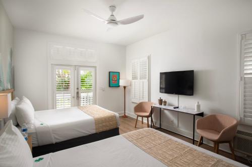 a hotel room with two beds and a flat screen tv at Paradise Inn - Adult Exclusive in Key West