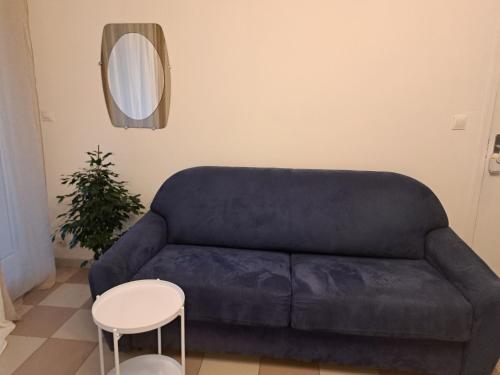 um sofá azul numa sala de estar com uma mesa e um espelho em Grand Studio de 24m2 avec terrasse privée proche de la gare RER TER em Étampes