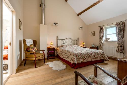 a bedroom with a bed and a chair and a window at Kidwelly Farmhouse B&B in Kidwelly