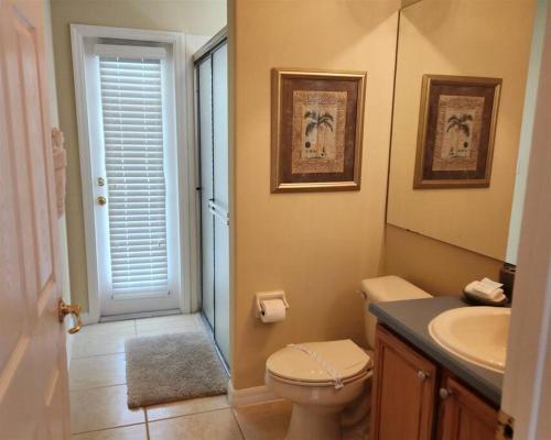 a bathroom with a toilet and a sink and a mirror at 35 - Relax & Play 4-Bed Villa with Pool & Game Room Minutes to Disney in Orlando