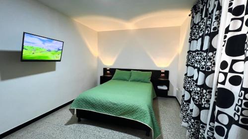 a bedroom with a bed with a tv on the wall at Apartaestudio Reloj in Líbano