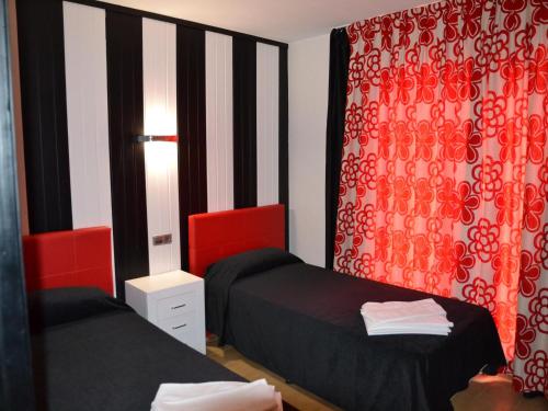 Apartamento L'Estartit, 2 dormitorios, 5 personas - ES-323-3 في لو ايسترتيت: سريرين في غرفة مع ستائر حمراء وسوداء