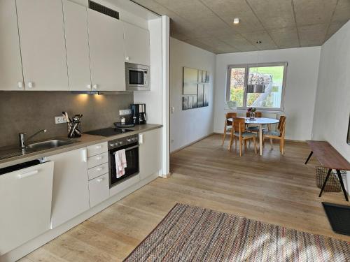 a kitchen with white cabinets and a table and a dining room at Naturresort Bieleboh in Beiersdorf