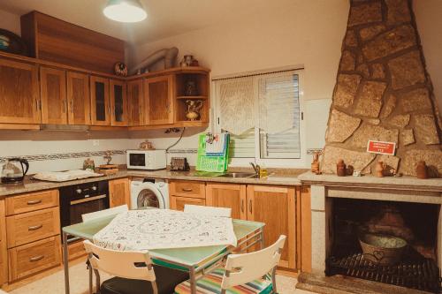 uma cozinha com uma mesa e uma lareira em Grandma's House em Penamacor
