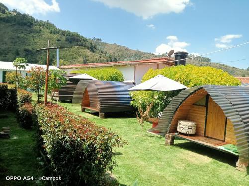 a group of huts in a yard with grass at CASA BAHAREQUE HOSPEDAJE in Monguí
