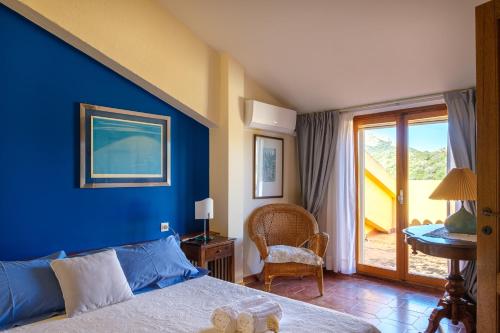een slaapkamer met een blauwe muur met een bed en een stoel bij [Portisco-Costa Smeralda] Villa Giardino e Vista Mare in Marina di Portisco