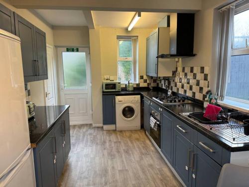a kitchen with blue cabinets and a washing machine at Home in Sheffield with King/Twin bed in Longley