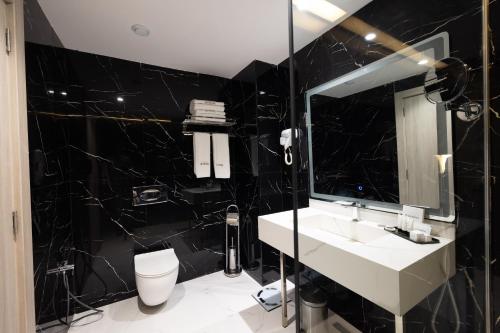Baño negro con lavabo y espejo en 2H Hotel en Orán