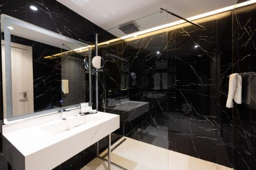 a black bathroom with a sink and a mirror at 2H Hotel in Oran