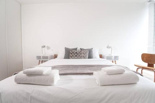 a white bedroom with a large white bed with towels on it at Luxury London Townhouse - Hidden Gem in London