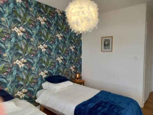 a bedroom with two beds and a floral wallpaper at Appartement plein centre de Valence d'Agen in Valence-dʼAgen