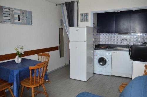 Il comprend une cuisine équipée d'un réfrigérateur blanc et d'une table avec des chaises. dans l'établissement Résidence LES NEFS DES SABLES - 2 Pièces pour 5 Personnes 24, à Port-Leucate