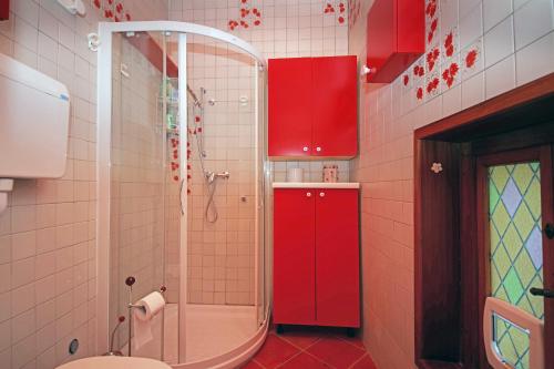 La salle de bains est pourvue de placards rouges et d'une douche. dans l'établissement Casale Massina APPARTAMENTO PERLA, à Salò