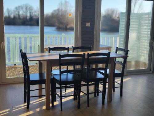 a dining room table and chairs with a view of a lake at Domaine de la roselière • Nature • Brenne in Rosnay