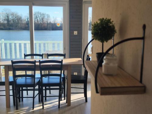 a dining room table and chairs with a view of the water at Domaine de la roselière • Nature • Brenne in Rosnay