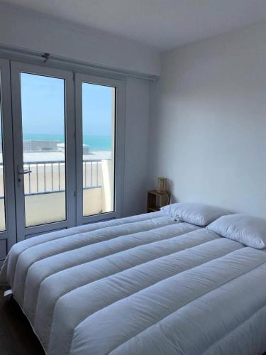 een witte slaapkamer met een groot bed en ramen bij Résidence Casino - 2 Pièces pour 4 Personnes 474 in Pléneuf-Val-André