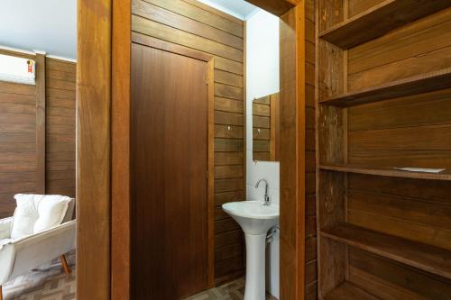 La salle de bains est pourvue d'un lavabo et d'un mur en bois. dans l'établissement Celeiro da Lagoa - Chalé confortável em meia à Natureza A apenas 8 km de distância da praia central de Balneário Picarras e a 15 Parque Beto Carrero World, à Balneário Piçarras