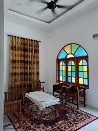 um quarto com cadeiras, uma mesa e um vitral em Homestay Legasi Haji Ali em Kuala Terengganu