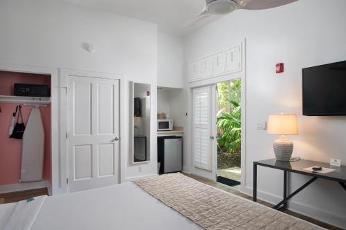 a white living room with a television and a table at Paradise Inn - Adult Exclusive in Key West