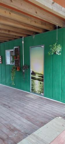 una pared verde con una puerta en un edificio en Morada Sol e Lua Container Guarda do Embaú com Ar condicionado en Guarda do Embaú