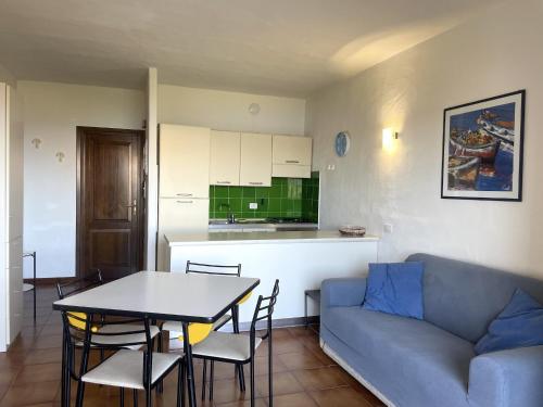 a living room with a couch and a table and a kitchen at Punta Est Giardino e Vista Mare in Capo Coda Cavallo