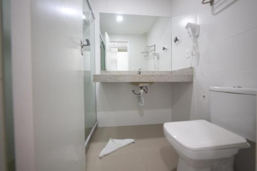 une salle de bains blanche avec toilettes et lavabo dans l'établissement Flat 426 comodidade na Passagem em Cabo Frio, à Cabo Frio