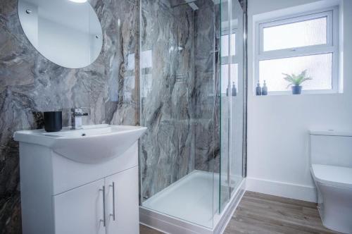 La salle de bains est pourvue d'un lavabo blanc et d'une douche. dans l'établissement Gower Hideaway - 3 Bed Apartment - Ocean Breeze, à Port Eynon